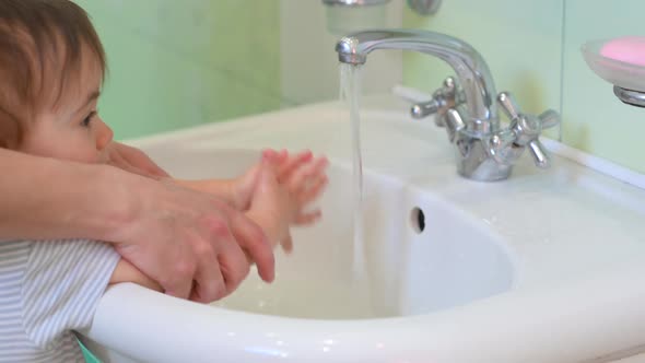 parent is teaching her son how to wash hands.