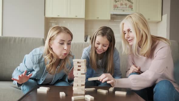 Three Generations of Women Playing Stack and Crash Board Game Together Smiling Young Woman with