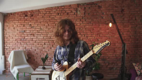 Portrait of Young Man Musician with Long Red Hair Playing Electric Guitar at Home Slow Motion