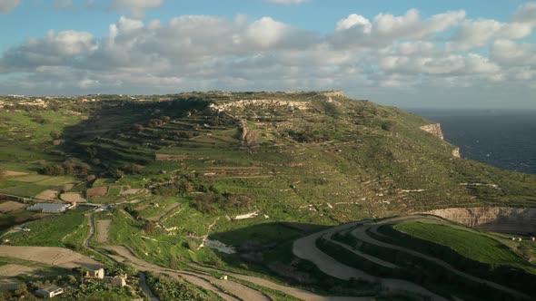 AERIAL: Sun Setting on Hills with Paddy Fields on a Warm Winter Evening in Malta