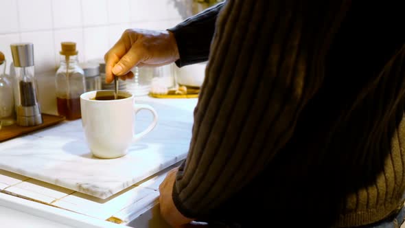 Man stirring coffee with spoon in kitchen 4k