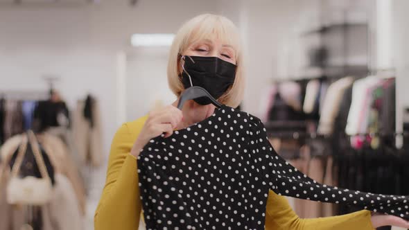Happy Mature Woman in Protective Mask in Clothing Store Joyful Female Customer Shopaholic Trying on