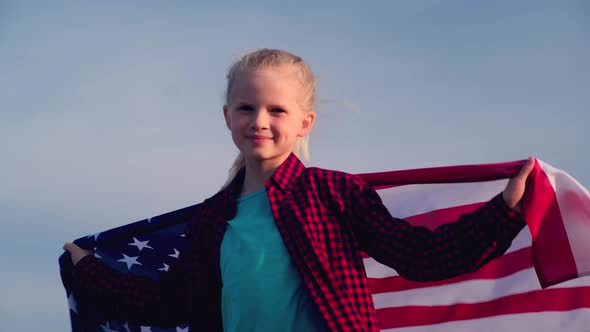 Blonde Girl Waving National USA Flag Outdoors Over Blue Sky at Summer American Flag Country