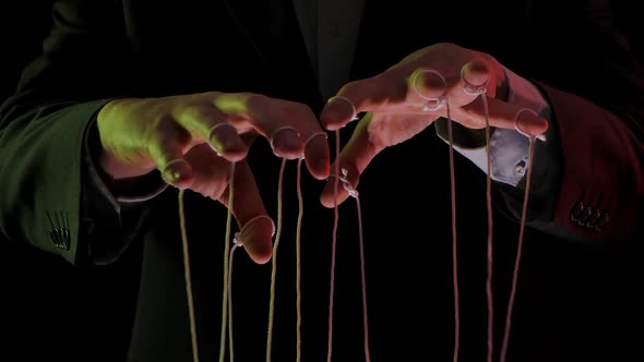Businessman Leader in a Suit Manipulates the Strings of Puppets Tied To His Fingers