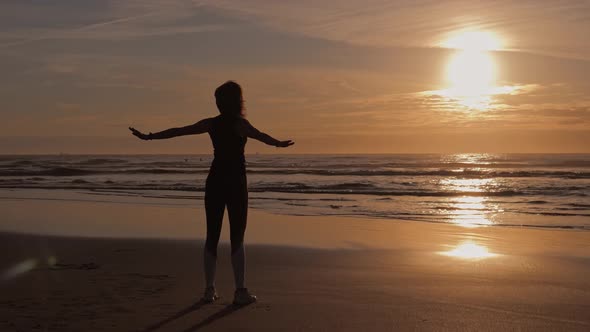 Slim Woman Jogger on the Seashore Doing Stretching Exercises