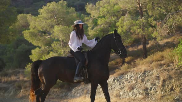 Side View of Positive Professional Caucasian Equestrian Talking to Horse Sitting on Animal Back