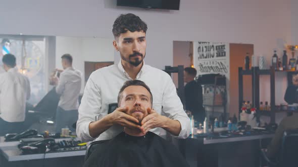 Barber Massaging Face of Man with Beard Before Shaving.