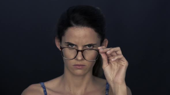 Woman looking over top of glasses with furrowed brow