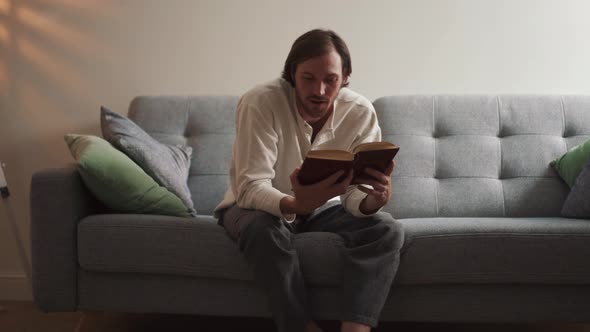 Positive long-haired man reading book