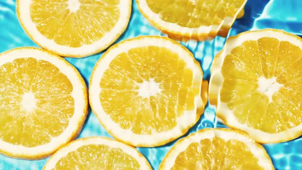 Macro Orange Fruit Slices and Blue Water Surface Texture with Ripple and Splash