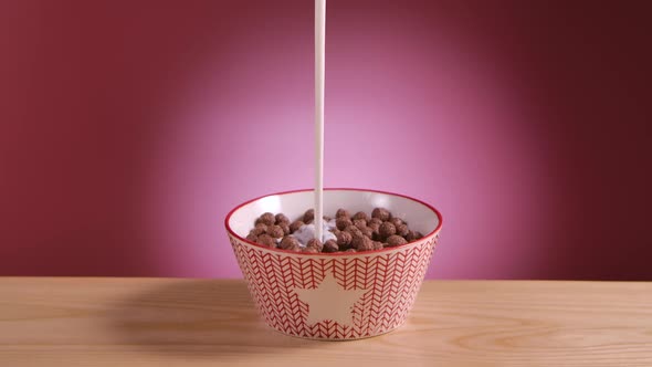 Cooking Delicious Breakfast of Chocolate Cornflakes in Form of Balls and Milk in Slow Motion on Pink