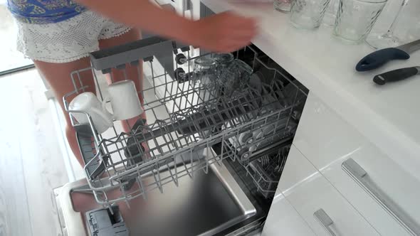 Woman Unloading the Dishwasher at Home