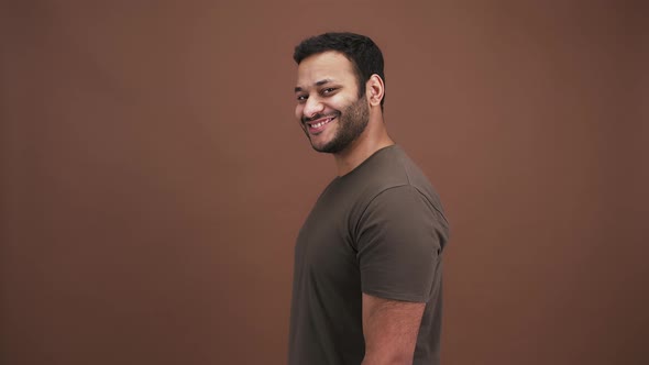 Playful Indian Man Flirting Pointing to Camera with Both Hands and Winking Brown Studio Background