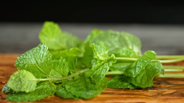 Super Slow Motion Shot of Fresh Mint Falling on Wooden Cutting Board at 1000Fps