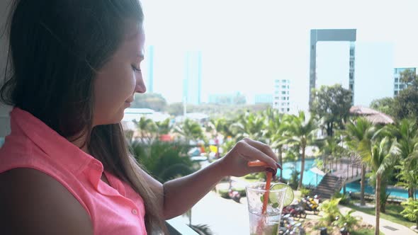 Girl Stands on Hotel Terrace and Drinks Sweet Tasty Mojito