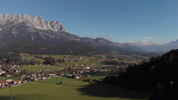 AERIAL: Flying over a valley of the alps with high mountains in the back