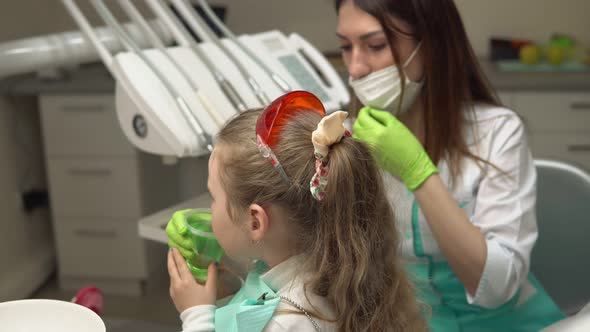 Little Cute Girl Rinsing Her Mouth with Treatment at the Dentist