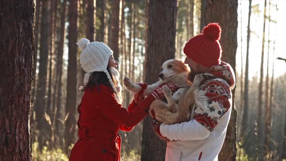 Happy Young Couple Hugging in Winter Forest with Their Doggy