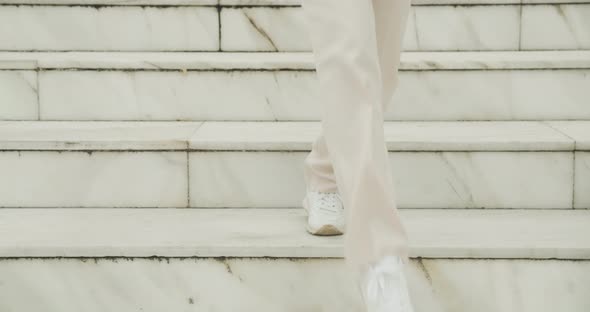 Woman In Sneakers Walking Down Marble Steps