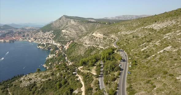 Aerial shot of Dubrovnik hills and roads with Old Town in the distance