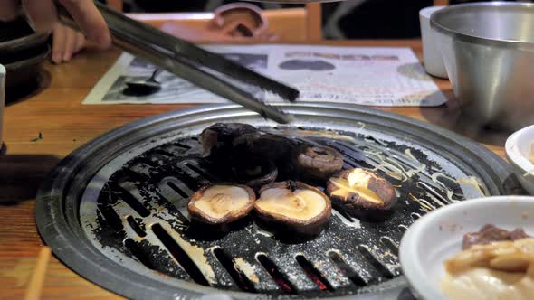 The Cook Prepares Mushrooms on Korean BBQ Grill Plate