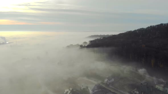 Flying Over the Fabulous Morning Mist Over the City. The Sunrise and the Colored Rays Reflected in