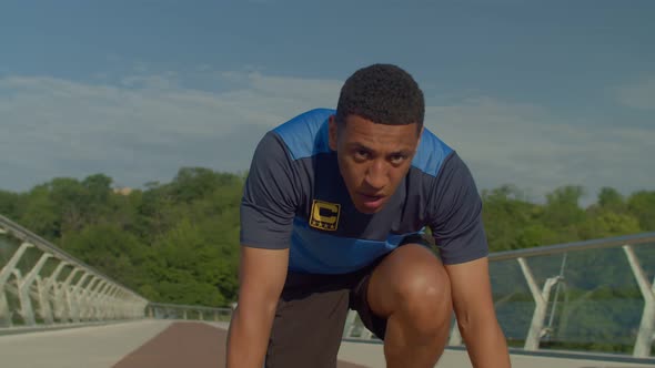 Portrait of Concentrated Black Male Runner in Start Position Preparing for Race