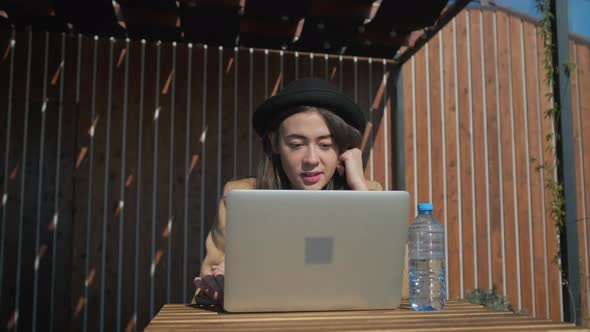 Teenage Girl Is Resting in Park Area, Browsing with Notebook