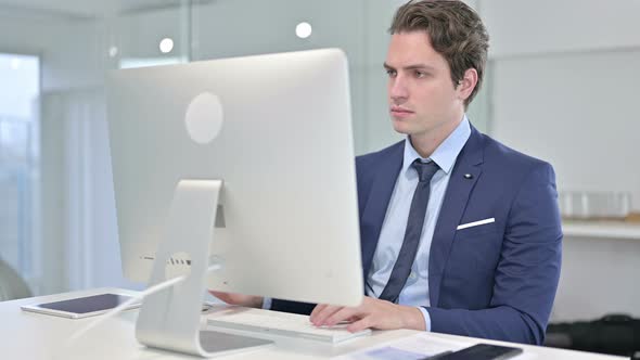 Focused Young Businessman Working on Desk Top in Office 