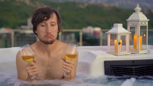 Sad Man with Wine Glasses is Sitting in a Hot Tub