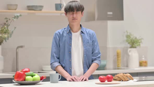 Asian Man Shaking Head As No Sign While in Kitchen