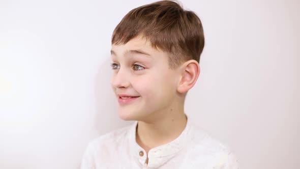 Little boy brushing his teeth on a white background