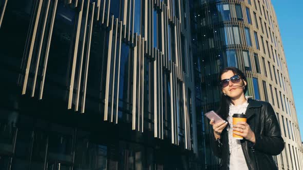 Young Attractive Businesswoman with Cup of Coffee Walking with Smart Phone in the City with Office