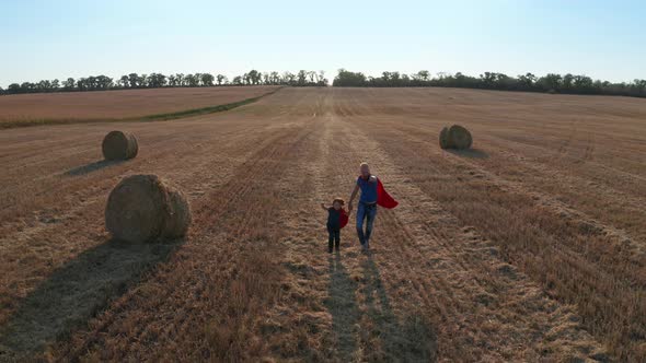Drone Shot of Father and Son Running Across Field