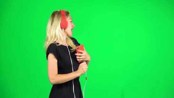 Girl Walks in Big Red Headphones and with a Smartphone, Switches Music and Dancing, Chroma Key, Slow