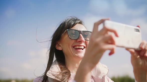 Happy Young Woman Taking Photo on Smartphone and Laughing