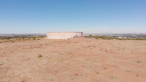 DRONE Reveal Shot of Water Supply Tank supplying water to a Town in the Background on a Sunny Day