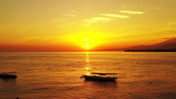 Beautiful golden sunset reflecting on the water with a scenic view of the mountains and anchored boa