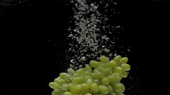 Slow Motion Green Grapes Falling Into Transparent Water on Black Background