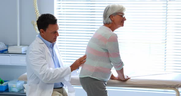 Physiotherapist giving back massage to senior patient