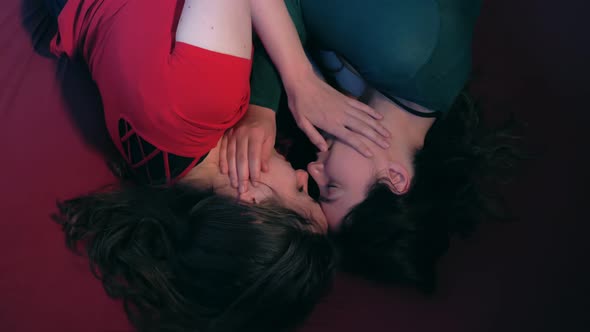 portrait of young beautiful lesbians lying on the bed hug each other