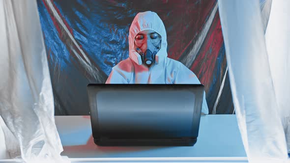 Researcher Wearing a Protective Suit is Operating a Computer