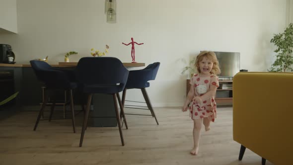 Front View Handheld Shot Happy Child Runs Through New Apartment in Pink Dress Along Corridor
