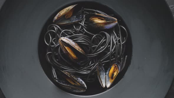 Close Up of Delicious Black Spaghetti Pasta Served with Mussels in Dark Plate