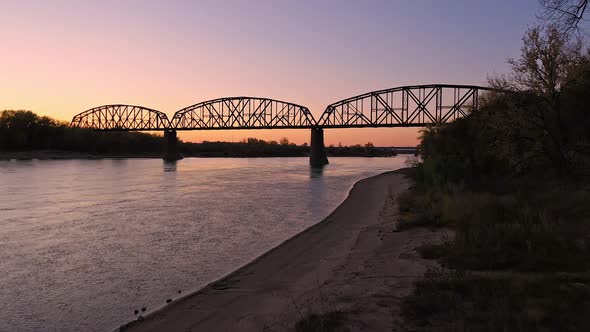 Aerial view flying up the shoreline of the Missouri River toward bridge