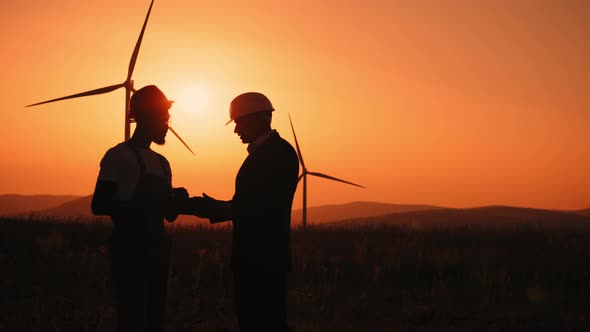 Silhouette Coworkers Examining Wind Turbines Using Modern Tablet Outdoors