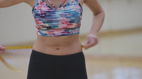 Woman at gym measures waist