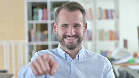 Portrait of Attractive Young Man Pointing with Finger 