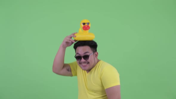 Happy Young Overweight Asian Man Holding Inflatable Duck Ready for Summer