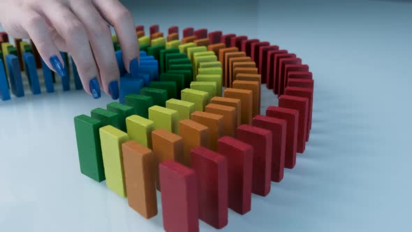 Line up of Dominoes in Rainbow Falling Colors with LGBT Colors of a Hand